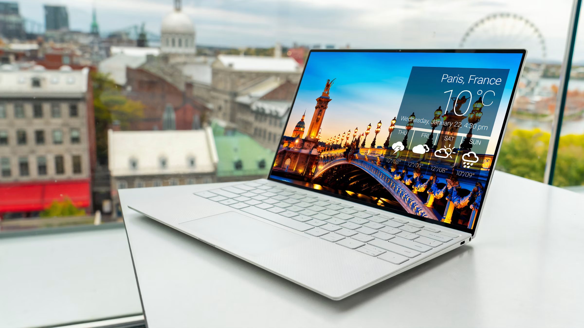 Laptop auf hellem Schreibtisch vor Stadtpanorama